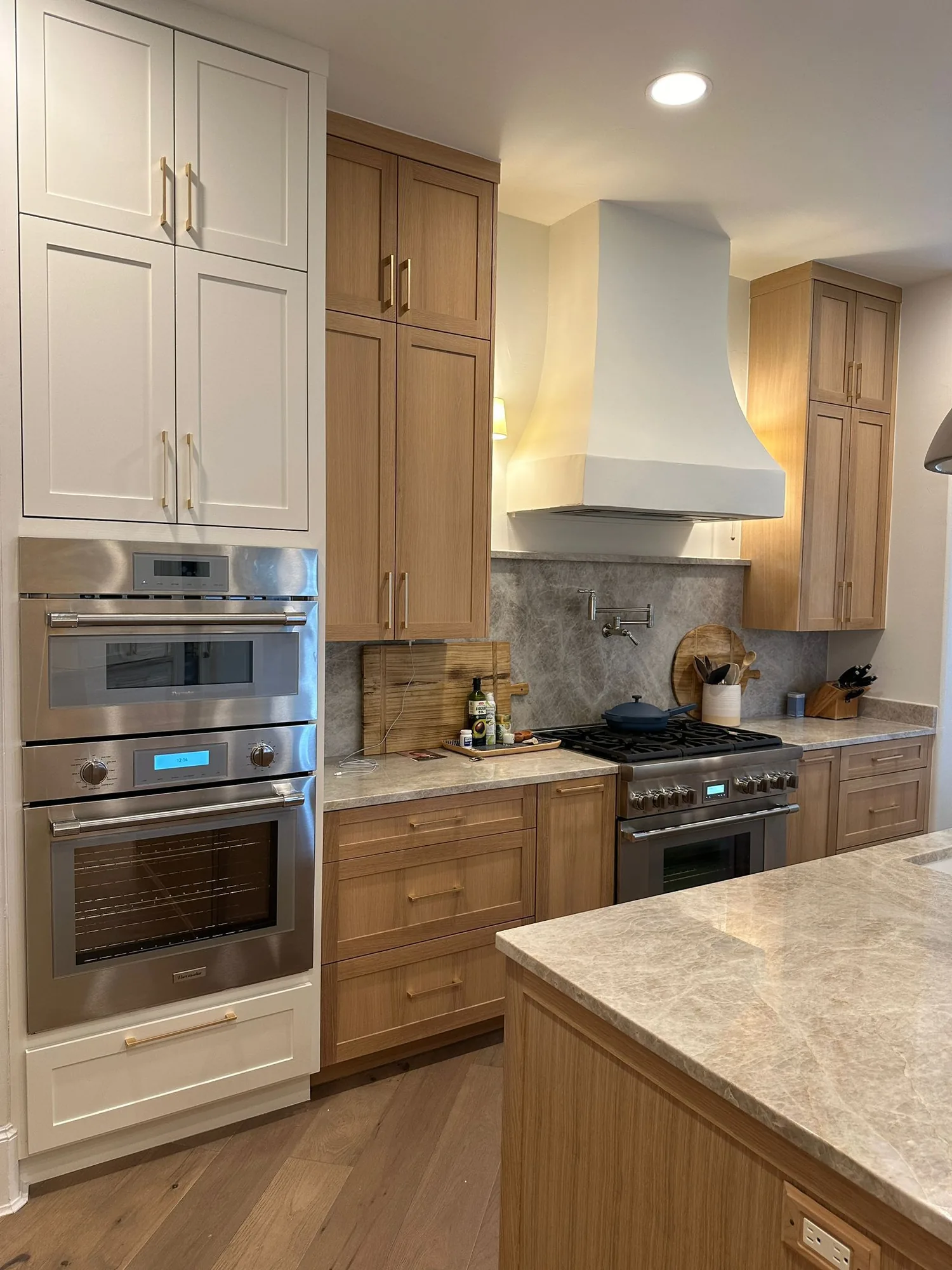 White oak and cream kitchen with brass hardware, built by Cabinet Central Austin