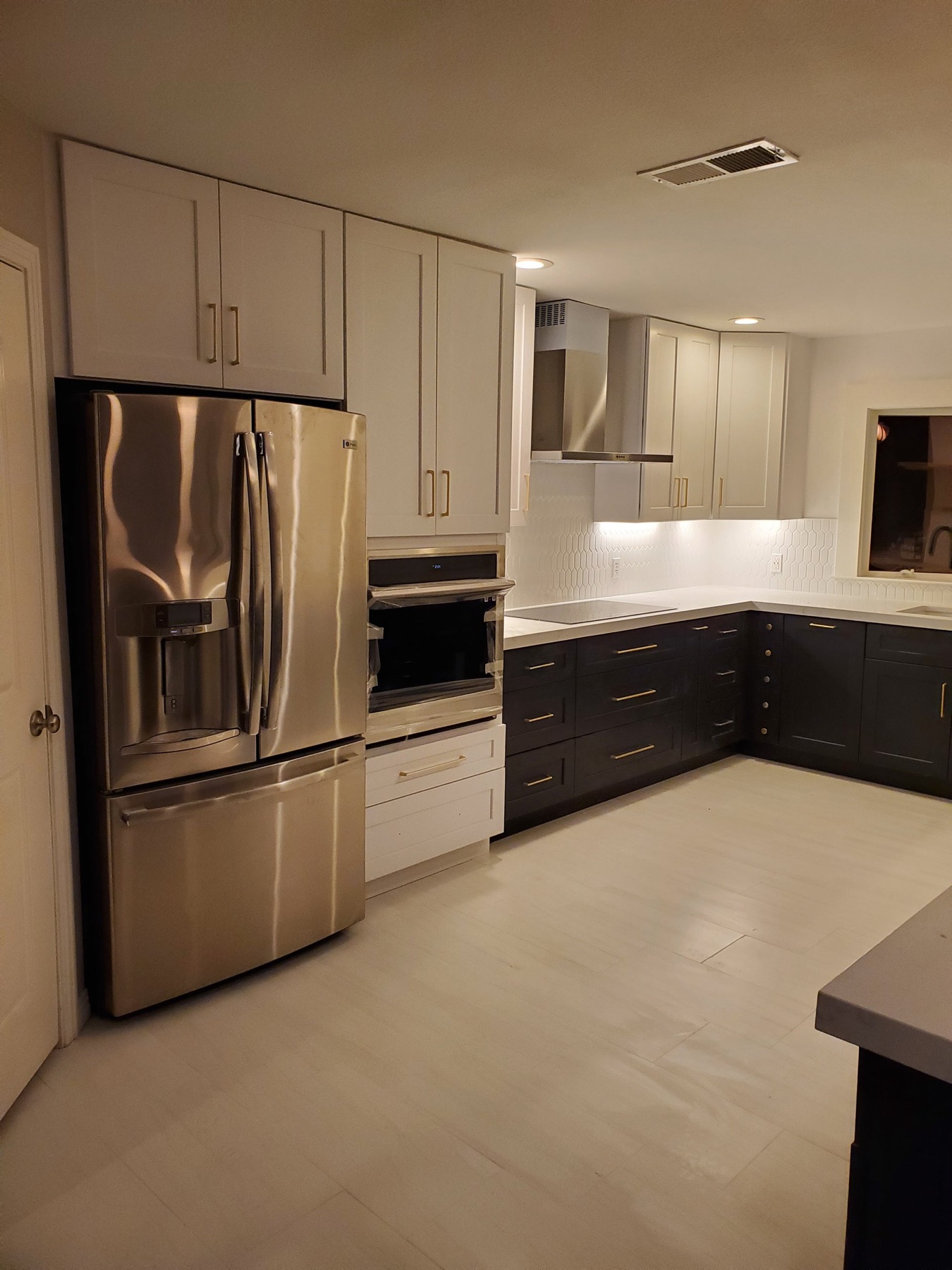 Two-tone kitchen with white uppers, charcoal lowers, and brass pulls