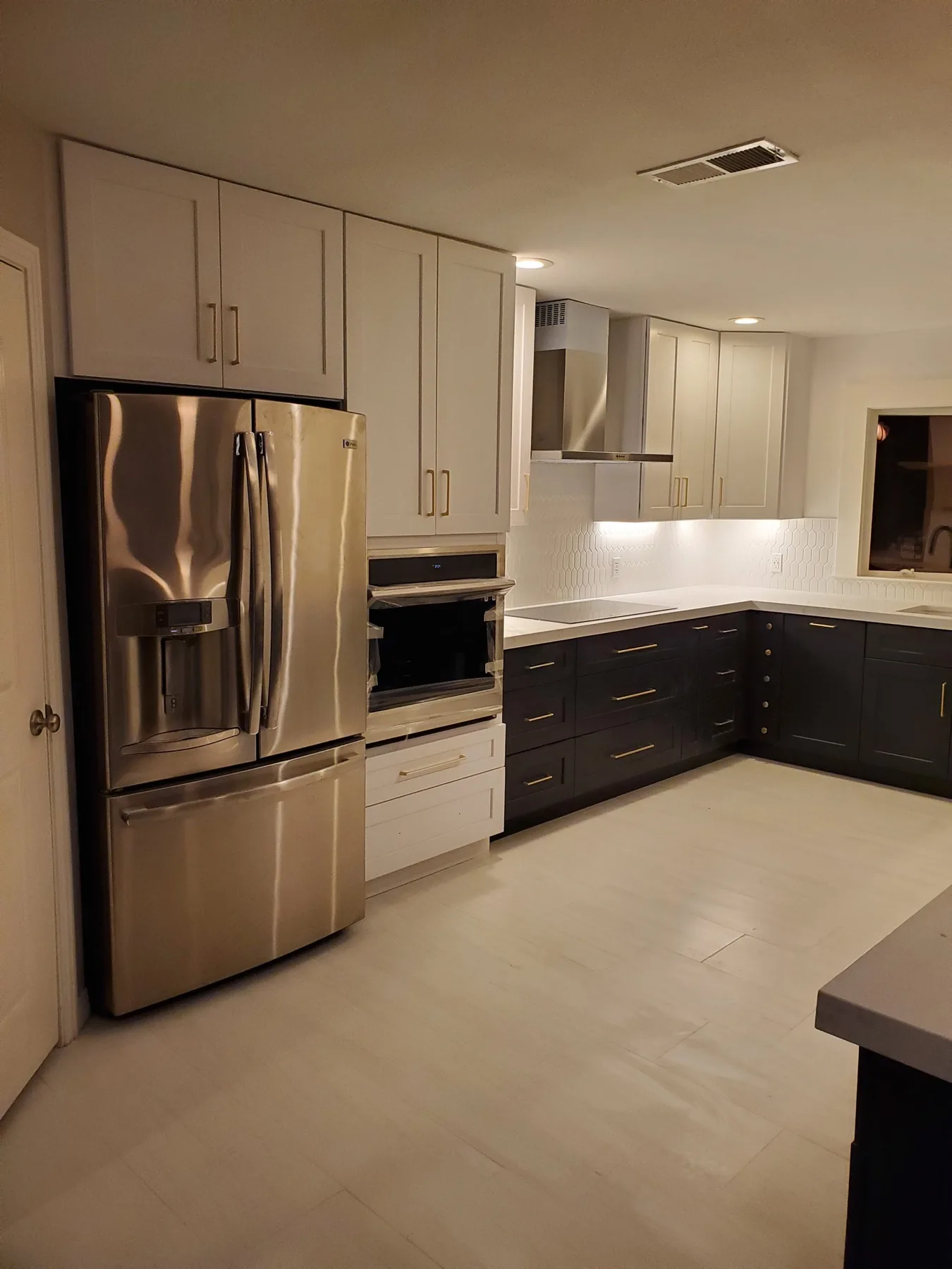 Two-tone kitchen with white uppers, charcoal lowers, and brass pulls